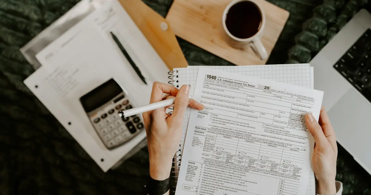 "Desk with tax documents, calculator, and coffee in warm daylight