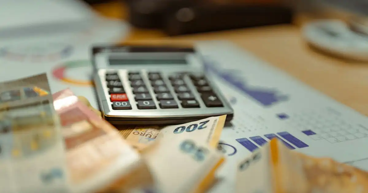 Desk with tax documents, calculator, and euro notes in warm daylight
