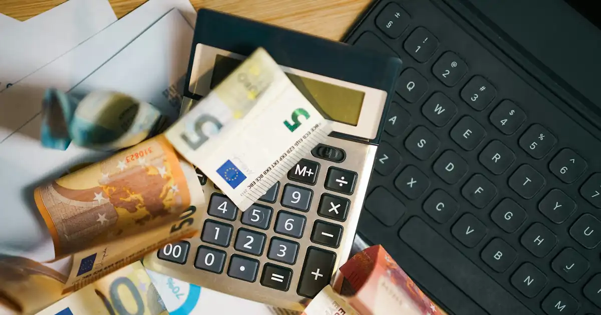 Desk with tax documents, calculator, and money in warm daylight