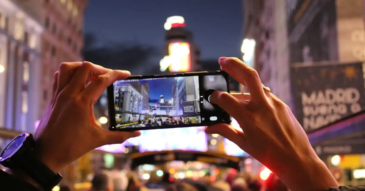 Person taking a cell phone photo at night in Madrid